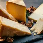 Plusieurs tranches de fromage avec noix et romarin sur ardoise