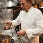 Chef en toque blanche préparant un plat à la cuisine