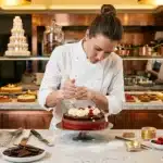 Chef pâtissière décore soigneusement un gâteau en cuisine professionnelle