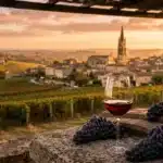 Verre de vin rouge avec raisins noirs, vignobles et église en arrière-plan